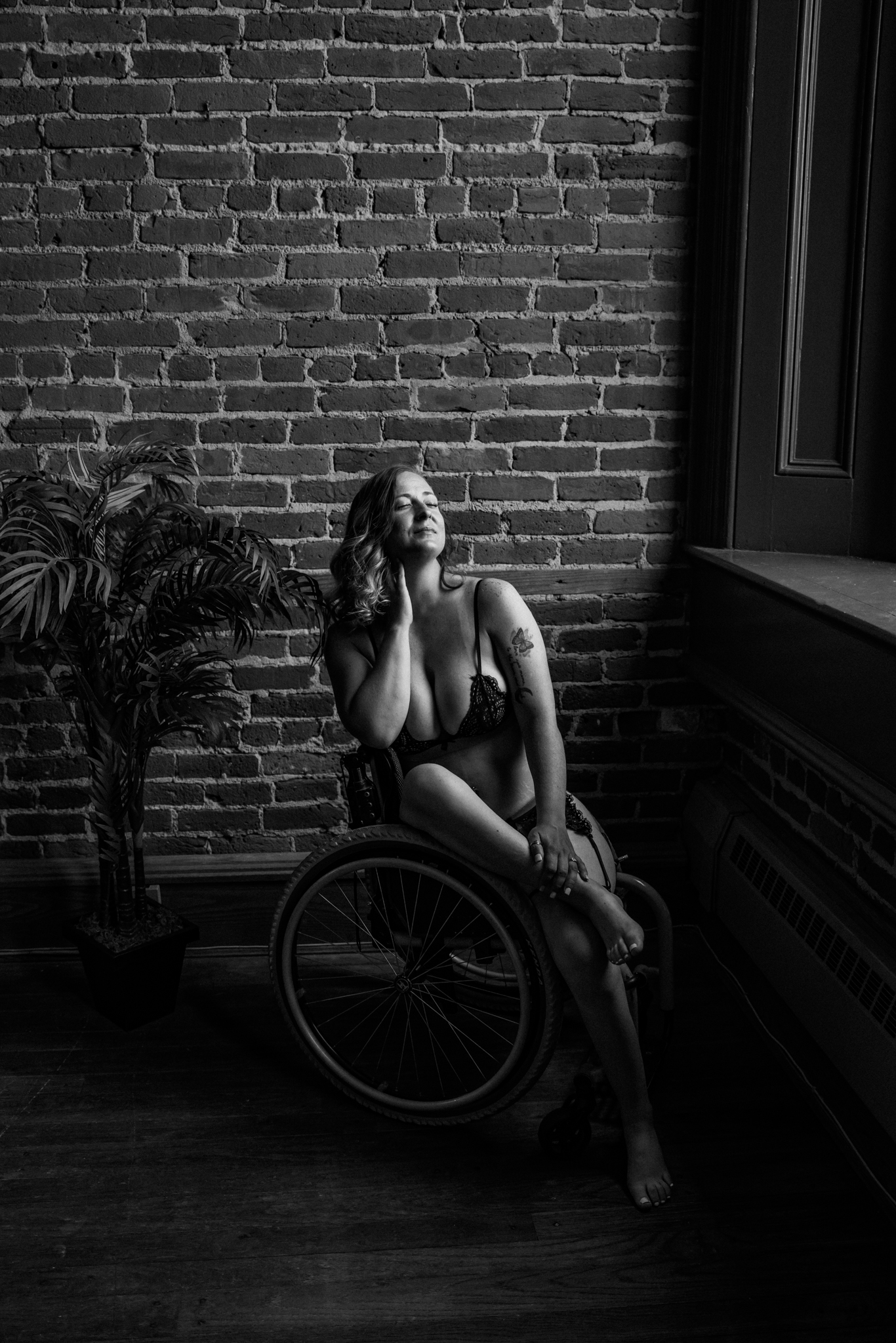 black and white boudoir image of a woman in a wheelchair next to a window