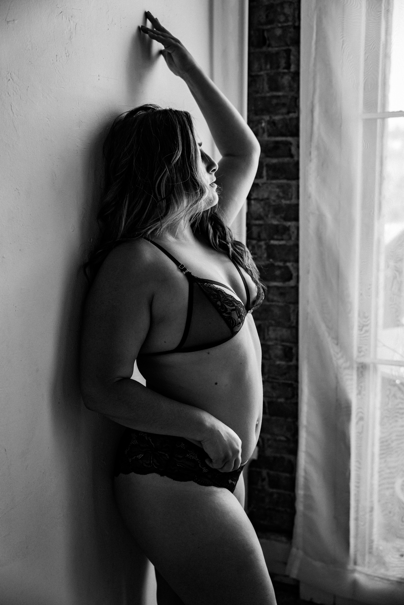 sexy black and white boudoir photo of a woman posing against a wall in black lingerie taken during a boudoir session in California