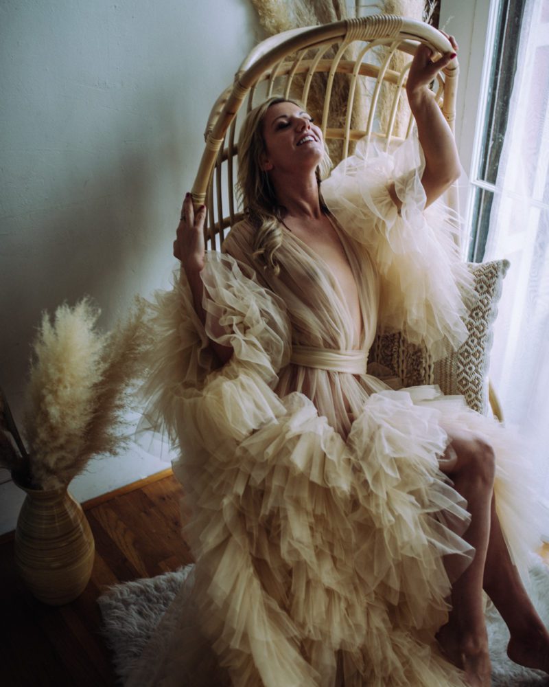 woman sits in a wicker chair in a gorgeous beige tulle dress during her photoshoot in Sacramento