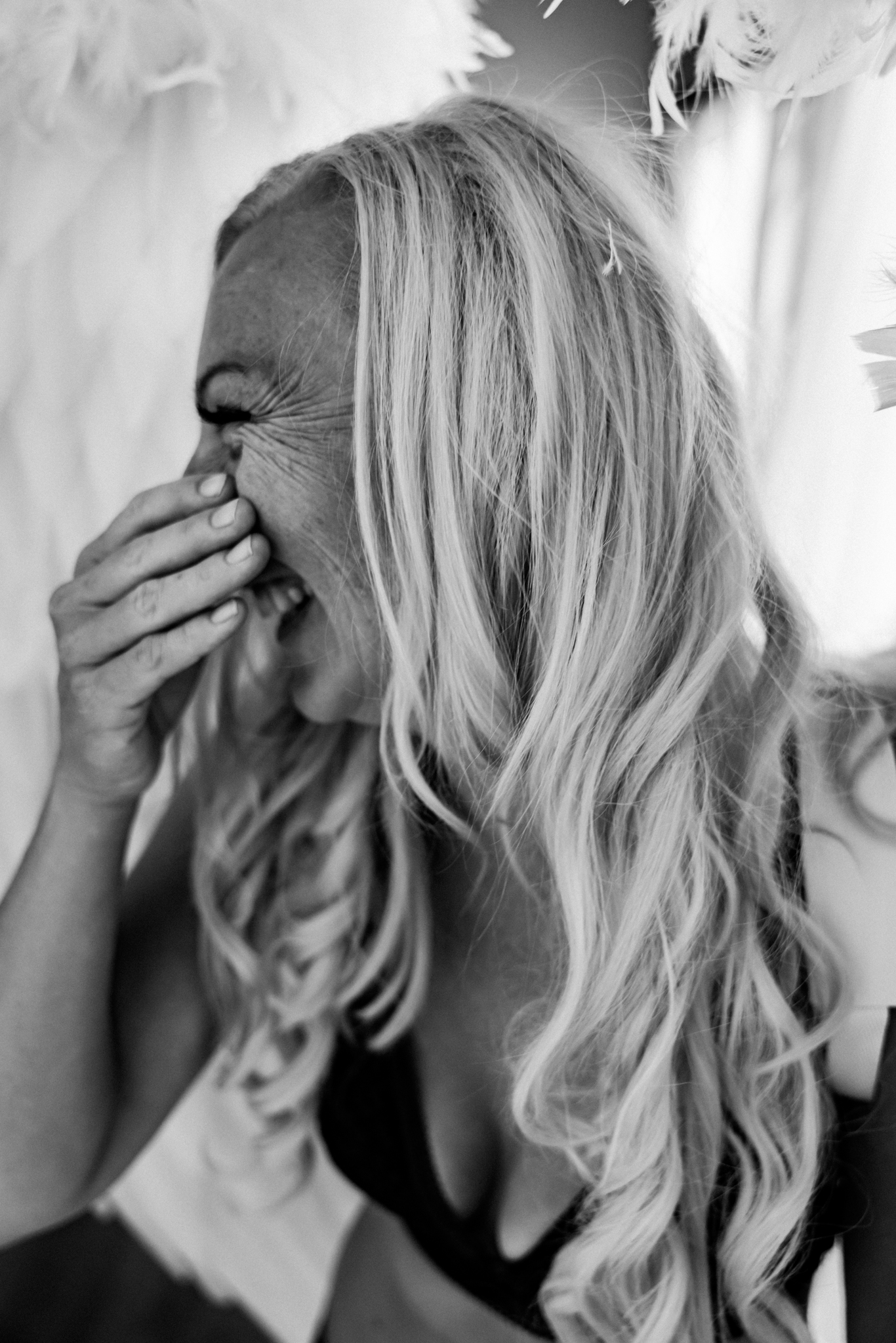 black and white photo of a blonde woman laughing during her boudoir session