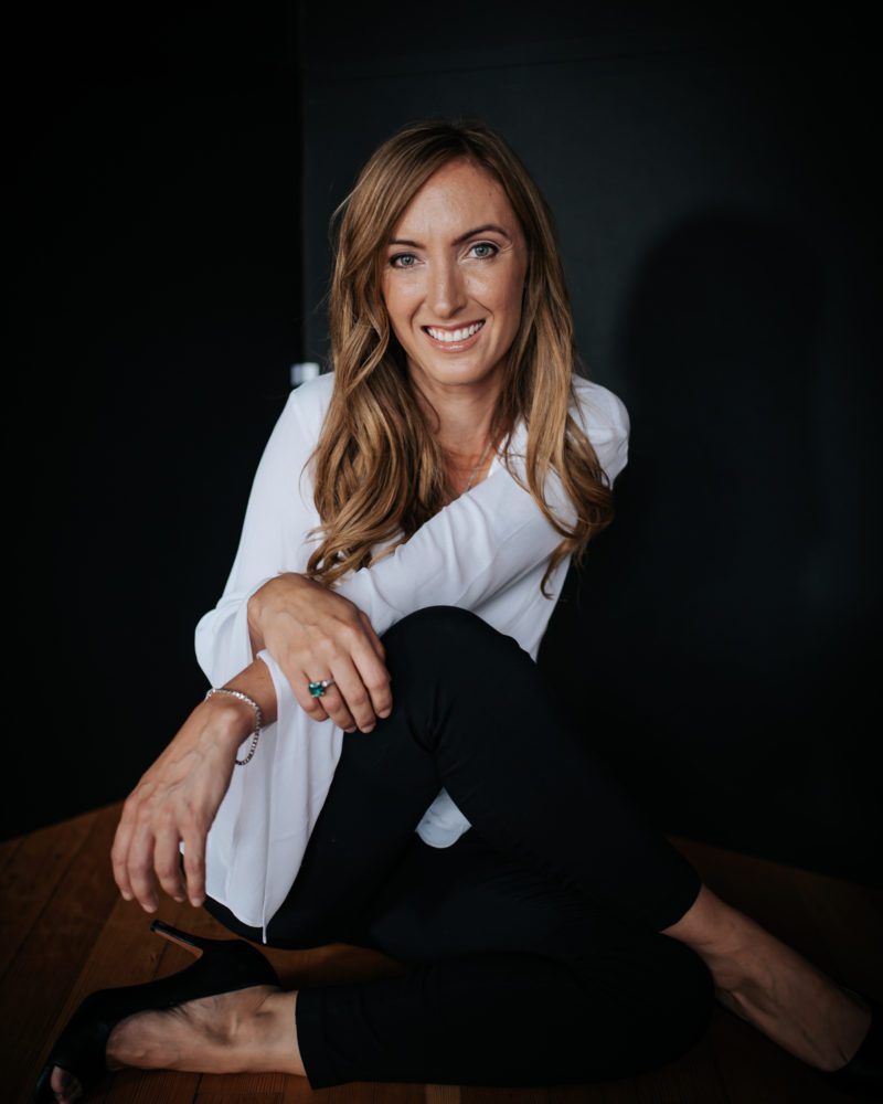 relaxed woman in a white shirt smiling while she gets her headshot taken in Humboldt County