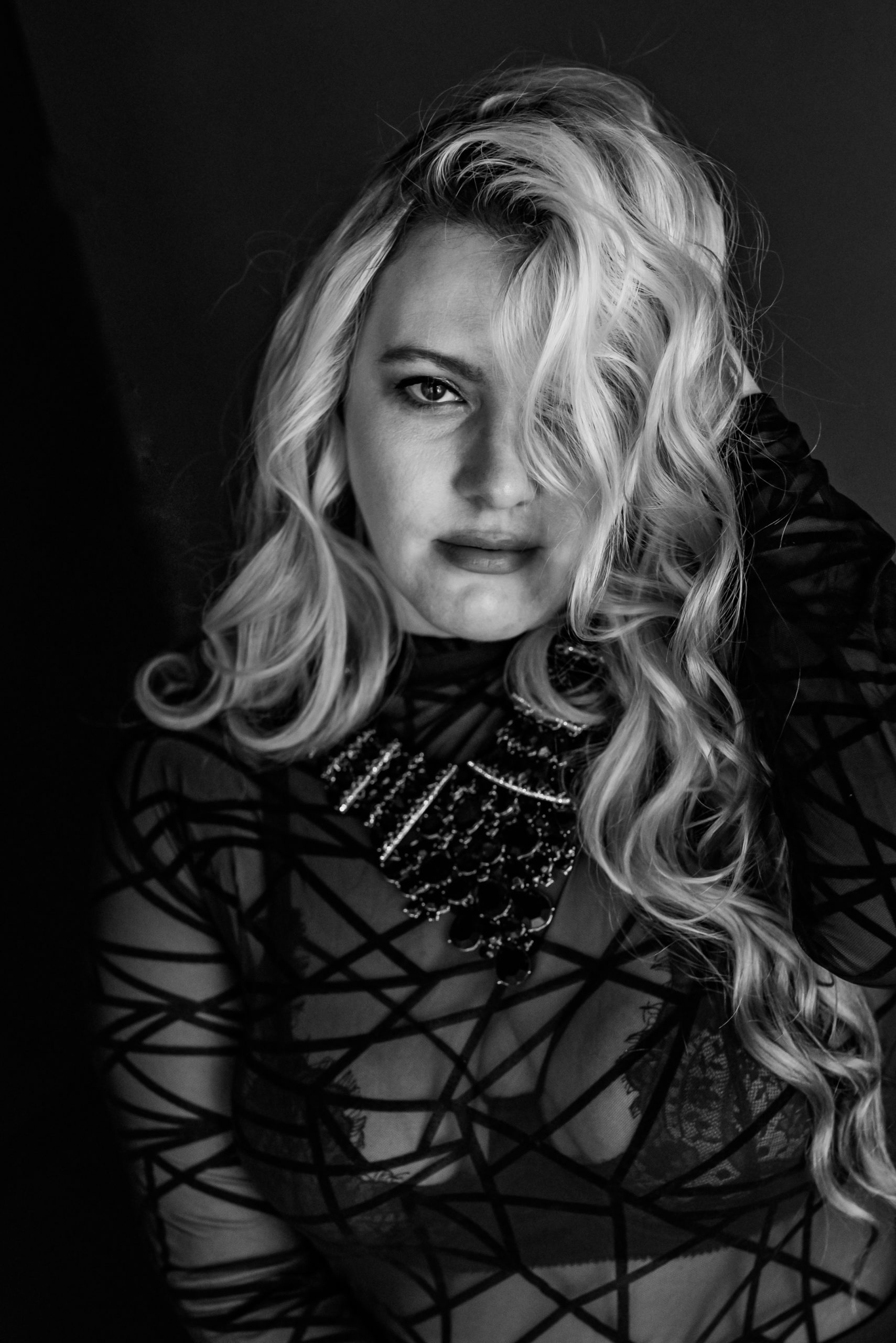 black and white headshot photo of a gorgeous blonde woman staring into the camera after her boudoir session