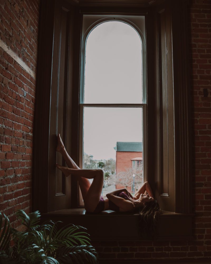 woman laying next to window striking the best boudoir poses for her photographer in Humboldt County