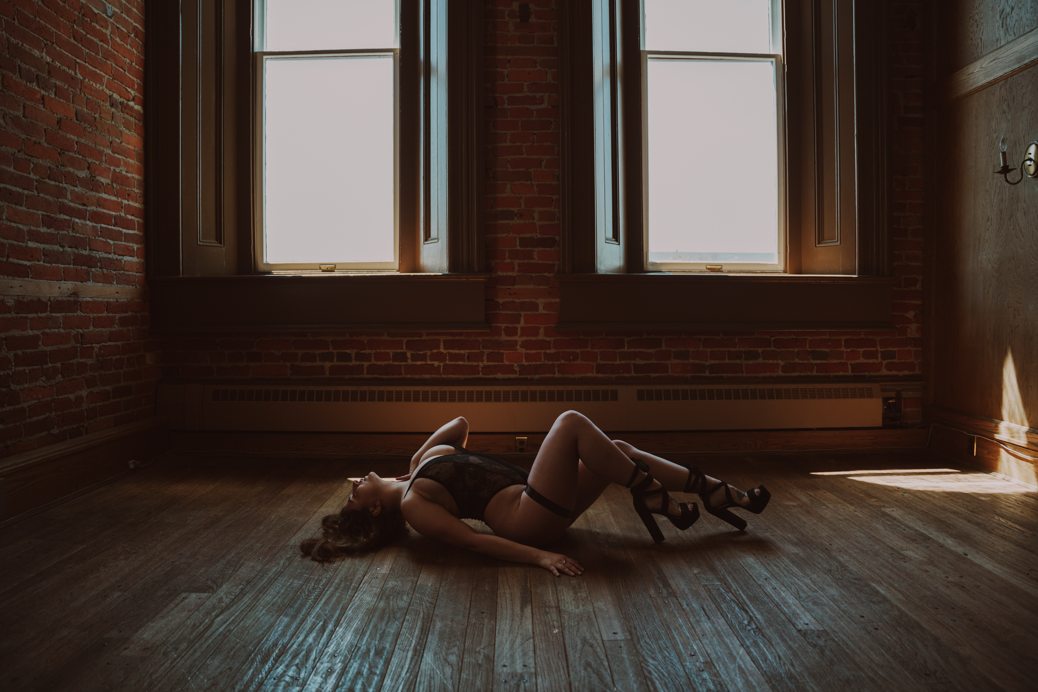 woman in black lingerie and heels poses on the floor of a studio during her photoshoot with Kimberly Ann Boudoir