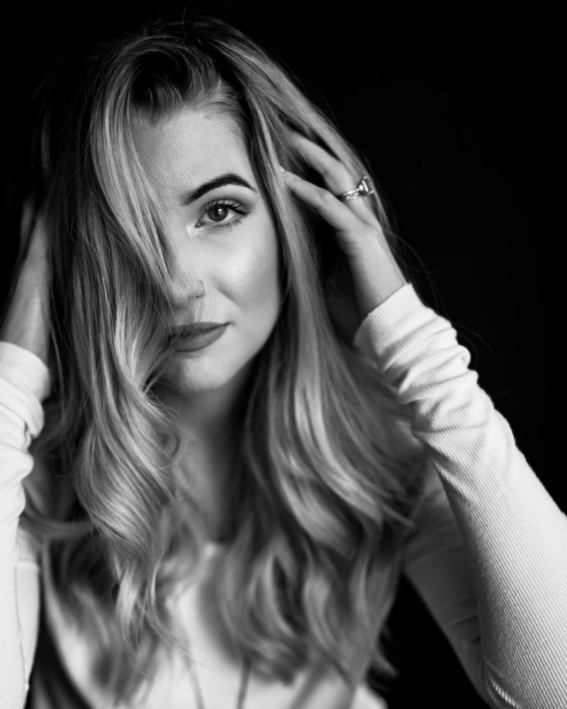 black and white photo of a woman with her hands in her hair posing for her luxe headshot photographer